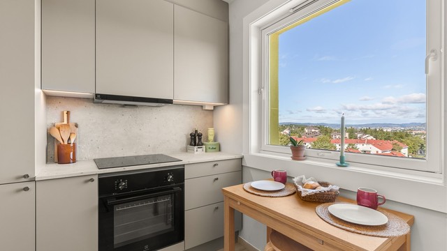 Moderne og tidsriktig HTH-kjøkken fra 2026 med stilrene, glatte fronter, gode arbeidsflater og rikelig med skap- og benkeplass. Det store vinduet slipper inn godt med naturlig lys og byr på en flott utsikt mot Østmarka og Østensjøvannet.