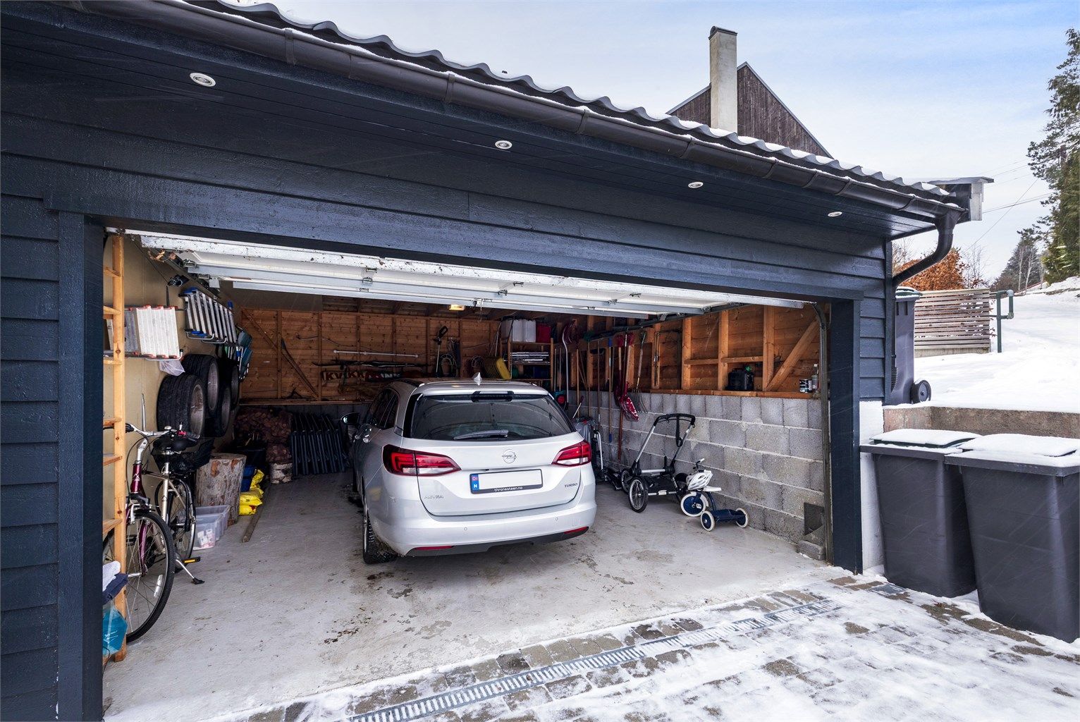 Garasje for en bil med fjernstyrt leddport. Garasjen er romslig med god plass til dekk og sykler