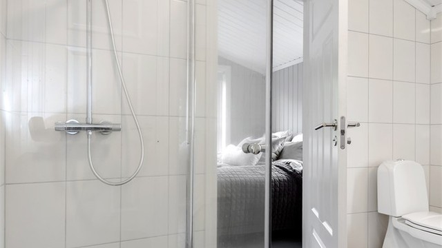 Badet har dusjnisje med glassvegg og trepanel i himling.