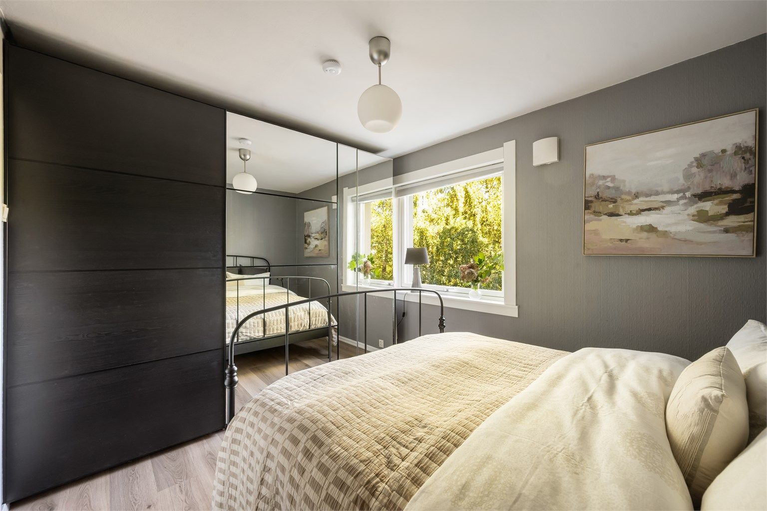 En stor skyvedørsgarderobe med speilfronter gir rikelig med oppbevaringsplass samtidig som speilflatene bidrar til en god romfølelse. Rommet har vindu mot grønne omgivelser.