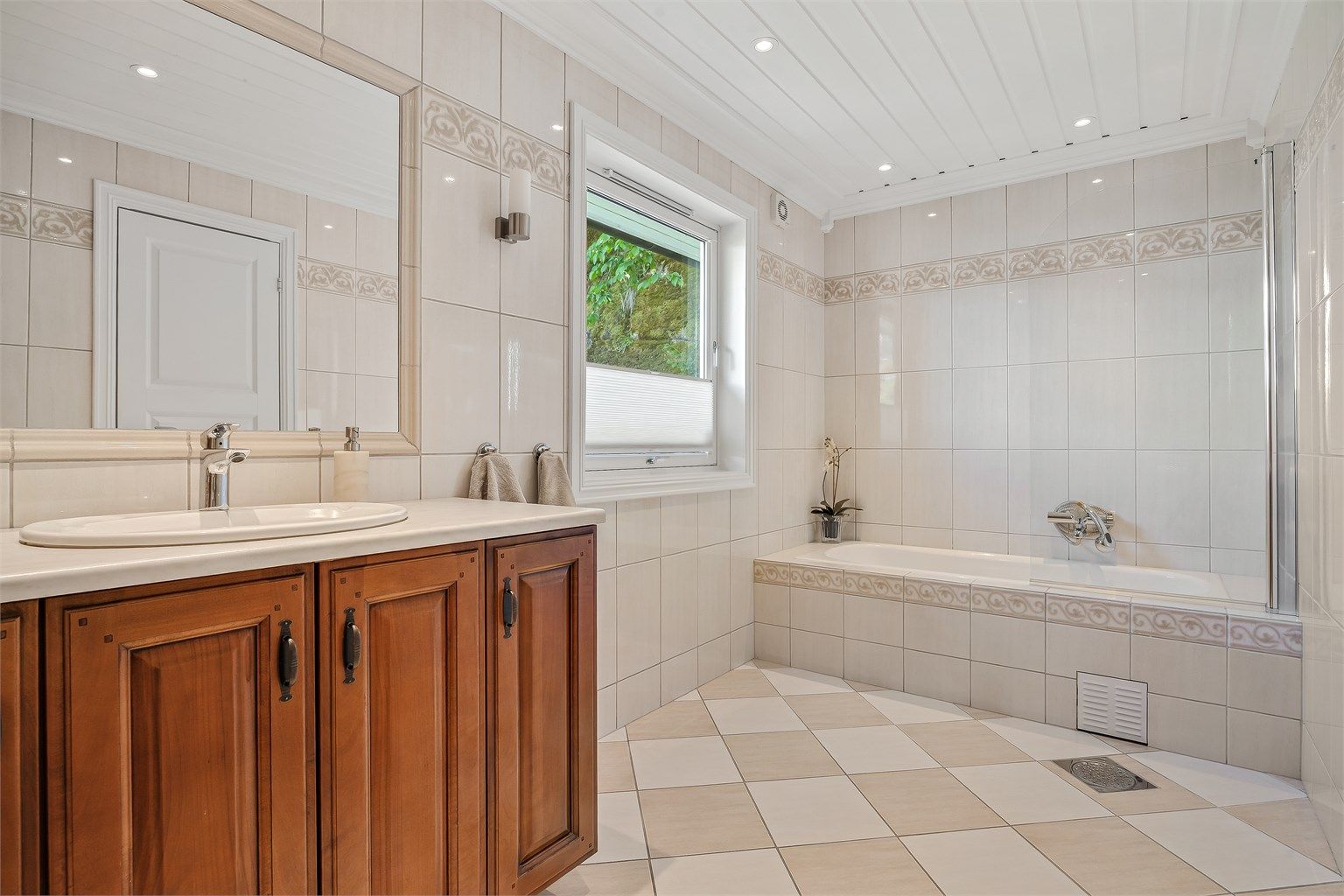 Badet i første etasje er flislagt og utstyrt med innfliset badekar samt varmekabler i gulvet.