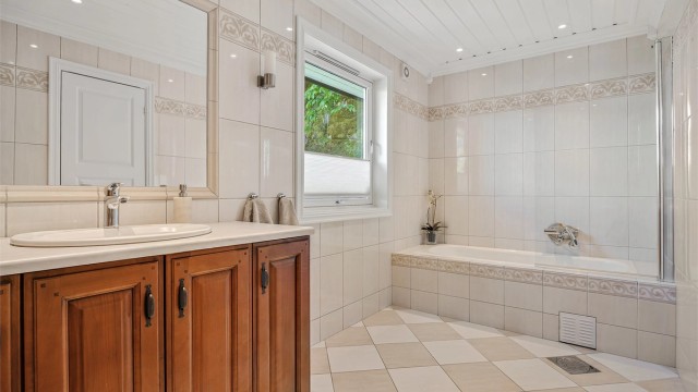 Badet i første etasje er flislagt og utstyrt med innfliset badekar samt varmekabler i gulvet.