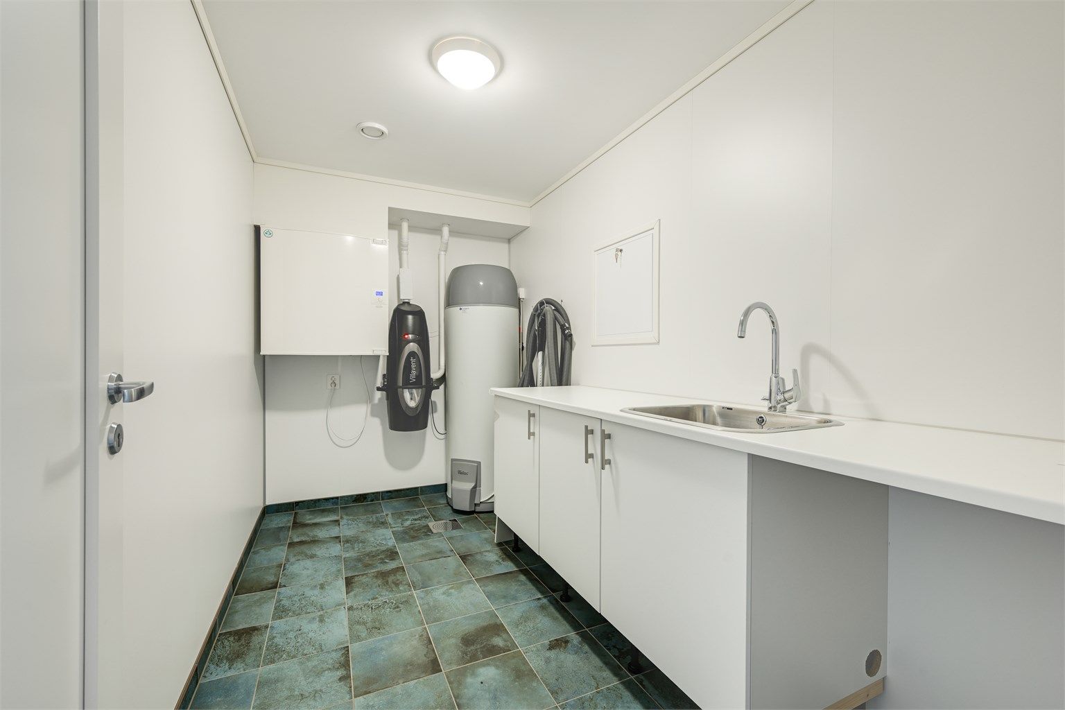 Separat vaskerom med egen inngang, flislagt gulv med varme og vaskeromsinnredning. Her er også boligens tekniske anlegg plassert.