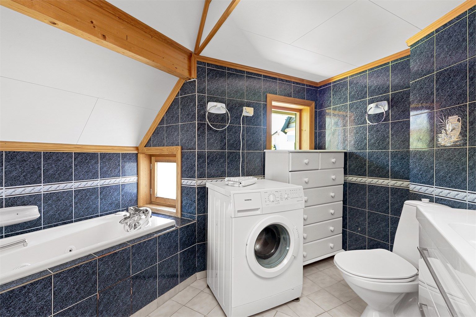 Badet har også et innfliset badekar og opplegg for vaskemaskin
