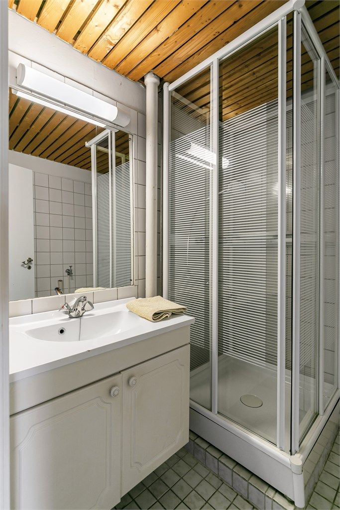 Badet har flislagt gulv med gulvvarme, dusjkabinett og opplegg for vaskemaskin.