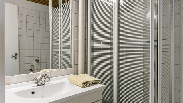 Badet har flislagt gulv med gulvvarme, dusjkabinett og opplegg for vaskemaskin.