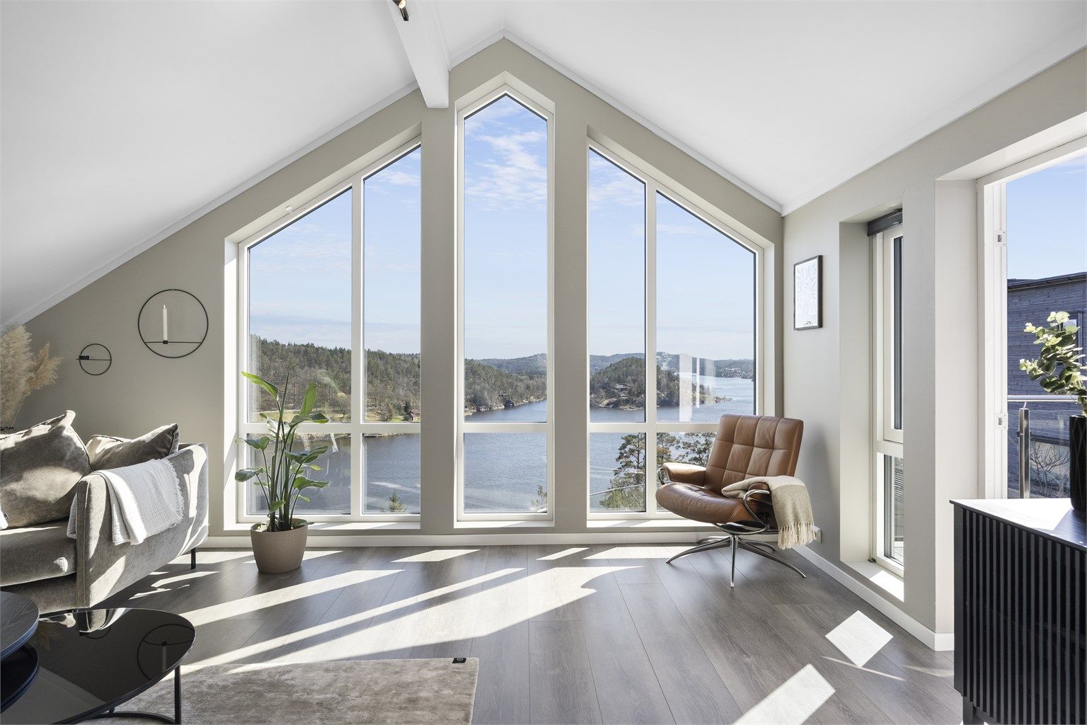 Loftstuen har en imponerende takhøyde og store vinduer som rammer inn den flotte utsikten over Tvedestrandsfjorden.