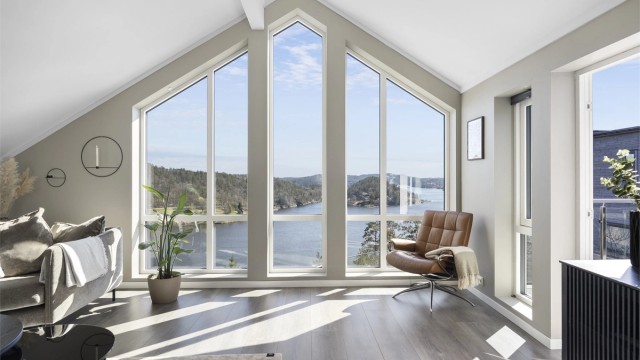 Loftstuen har en imponerende takhøyde og store vinduer som rammer inn den flotte utsikten over Tvedestrandsfjorden.