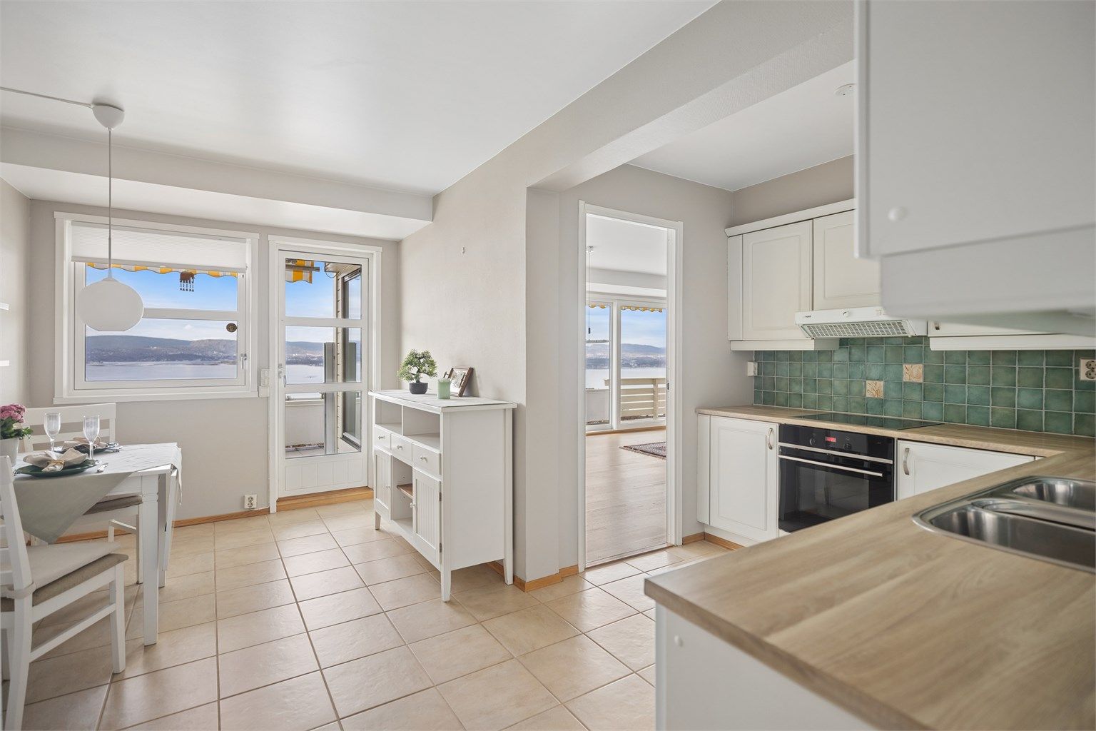 Kjøkkenet er holdt i delikate, lyse farger som gir rommet en rolig og elegant atmosfære, samtidig som paletten lar utsikten få hovedrollen