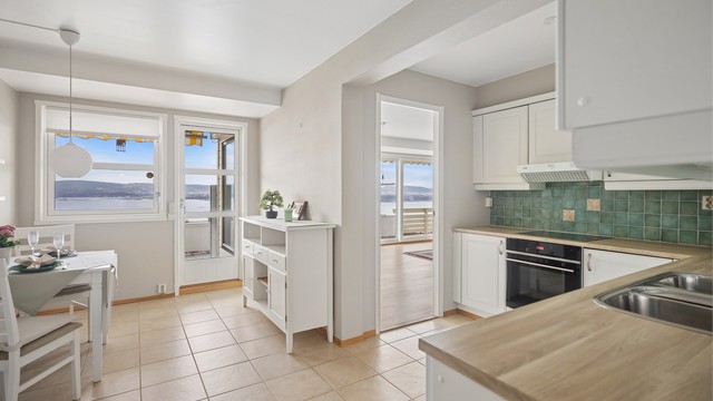 Kjøkkenet er holdt i delikate, lyse farger som gir rommet en rolig og elegant atmosfære, samtidig som paletten lar utsikten få hovedrollen