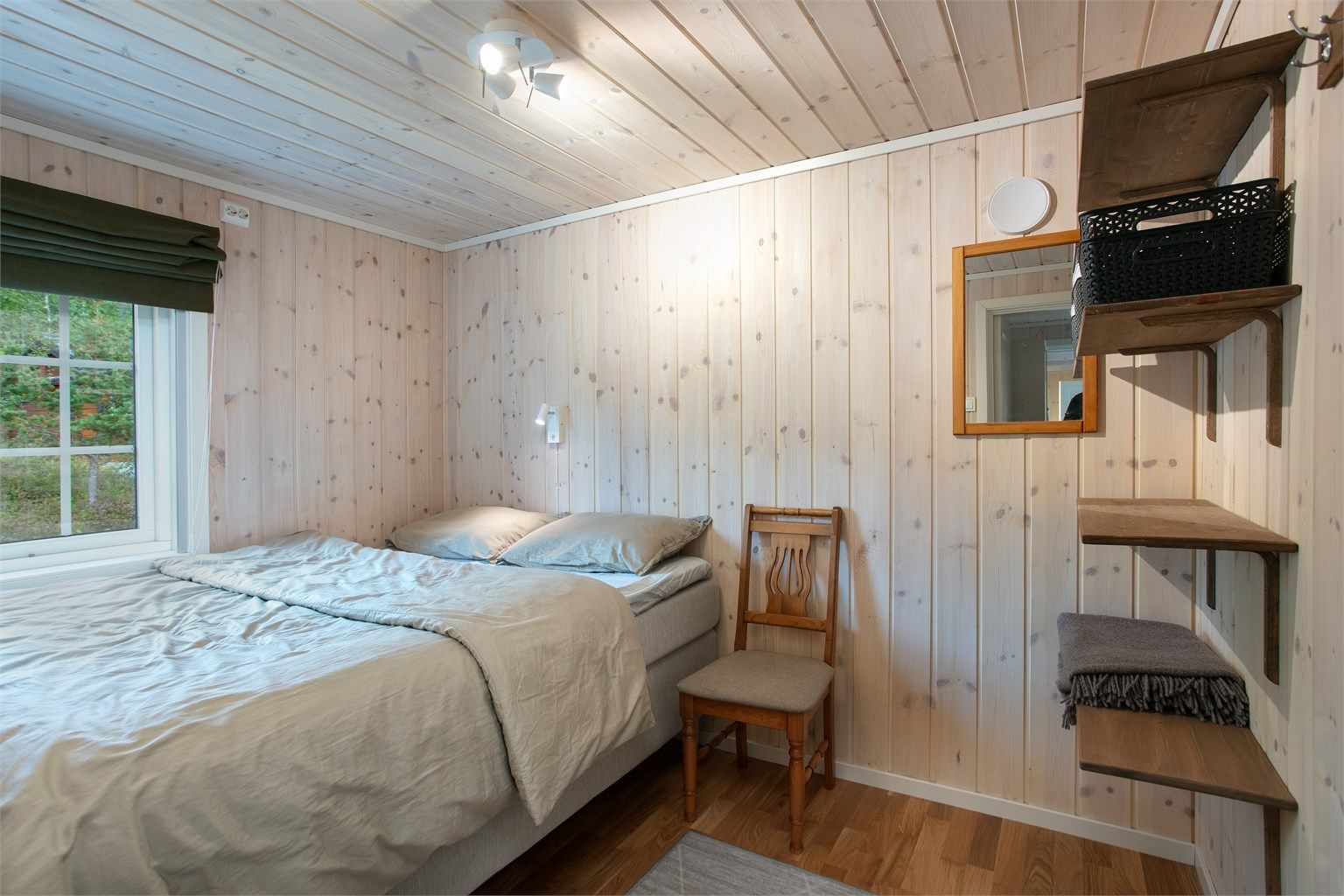 Soverom med plass til dobbeltseng, kledd med lasert trepanel.