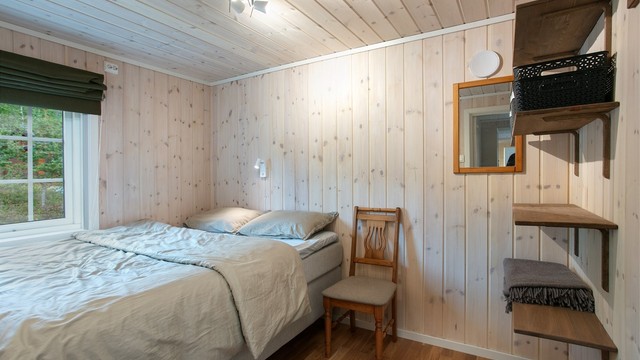 Soverom med plass til dobbeltseng, kledd med lasert trepanel.