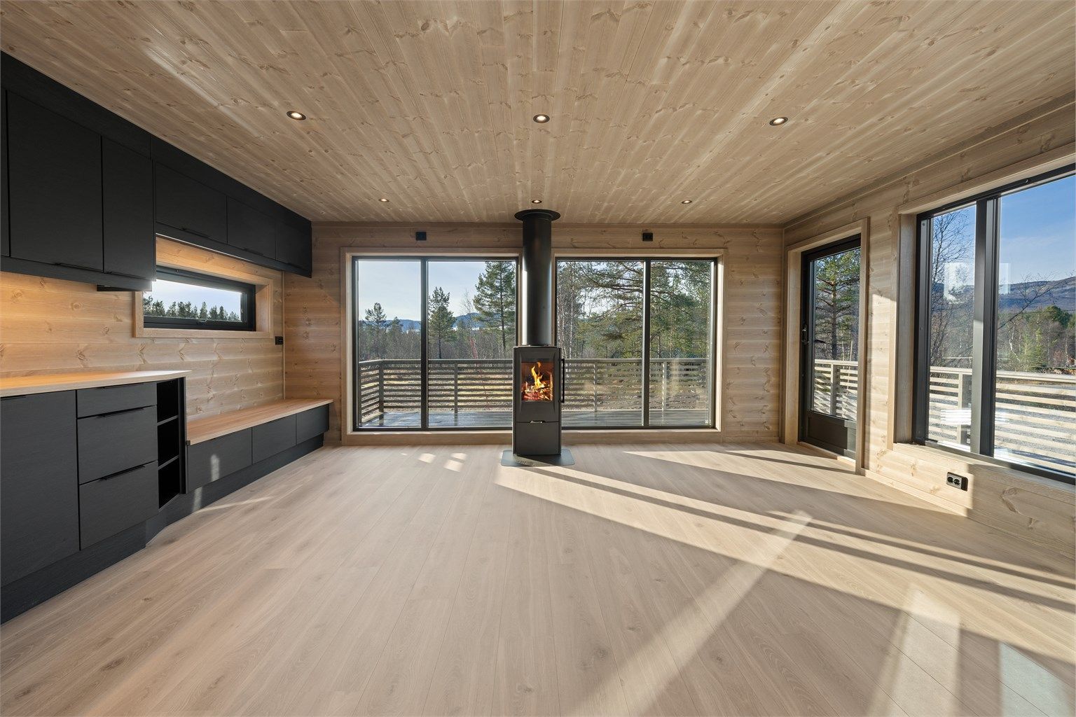 Stue med store vindusflater, flott utsikt, peisovn og utgang til solrik terrasse.