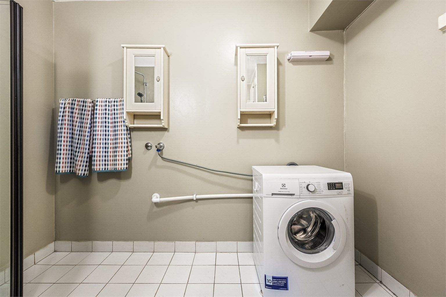 Badet har flislagt gulv og opplegg for vaskemaskin.