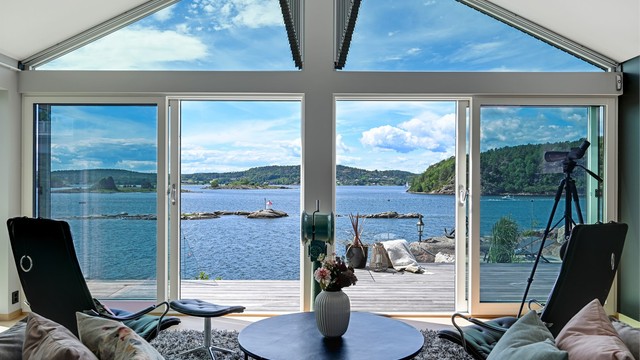 Det er adkomst ut til den flotte terrassen og hagen. Her får du sjøen rett inn i stuen.