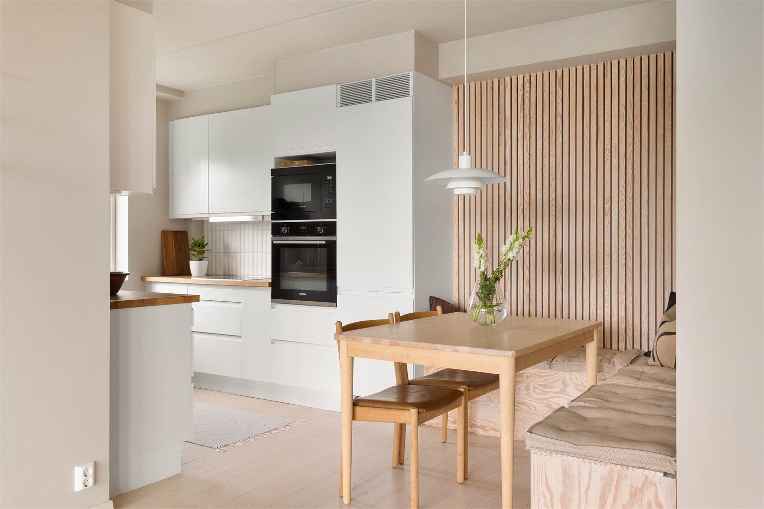Spiseplassen er smart plassert i tilknytning til kjøkkenet, med en dekorativ spilevegg som skaper en lun og innbydende atmosfære.