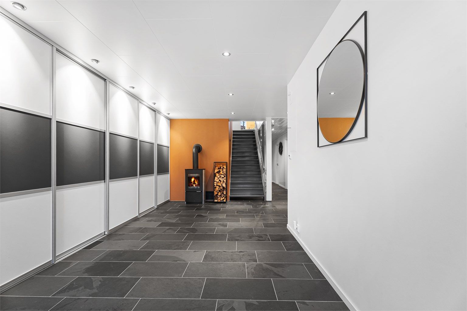 Pen flislagt hall med peis og varmekabler.