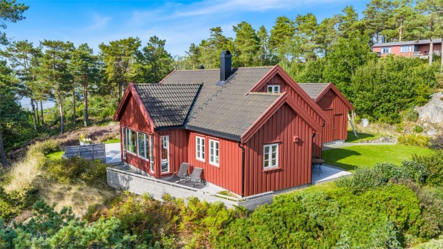 Usjenert og sjønær eiendom på Tromøy med fritidsbolig og anneks, omkranset av stor terrasse og naturskjønne omgivelser.