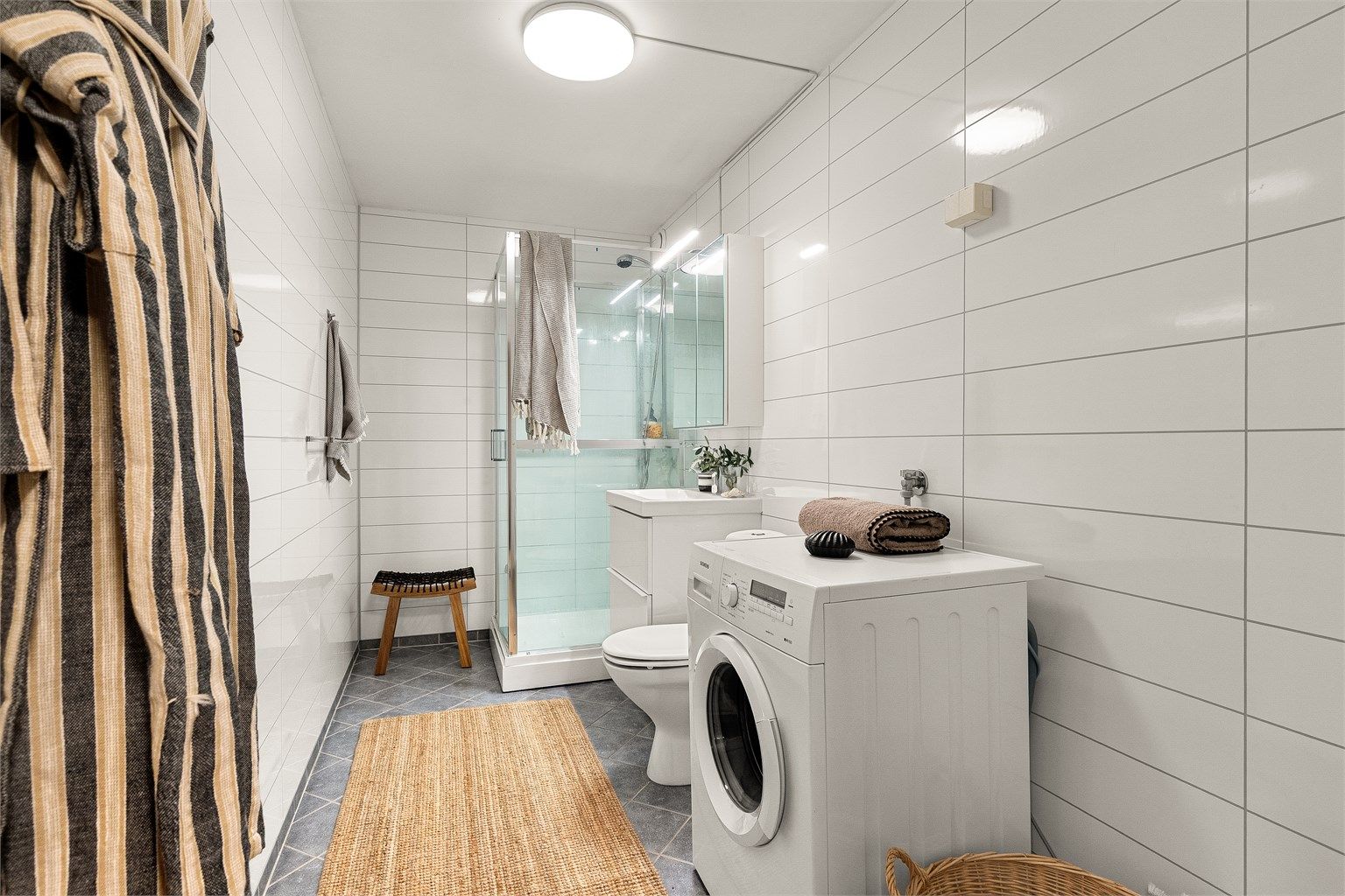 Pent bad med våtromsplater på veggene og flislagt gulv med gulvvarme.