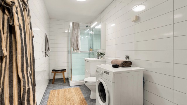 Pent bad med våtromsplater på veggene og flislagt gulv med gulvvarme.