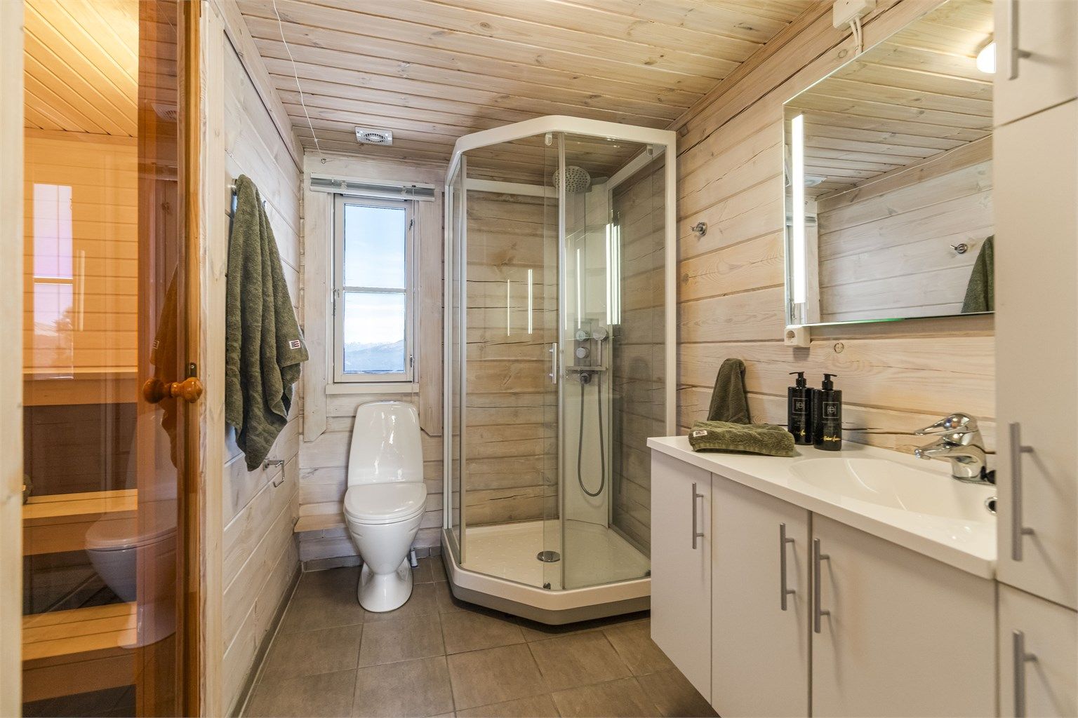 Badet i første etasje har flislagt gulv med gulvvarme, dusjkabinett og direkte tilgang til badstuen.