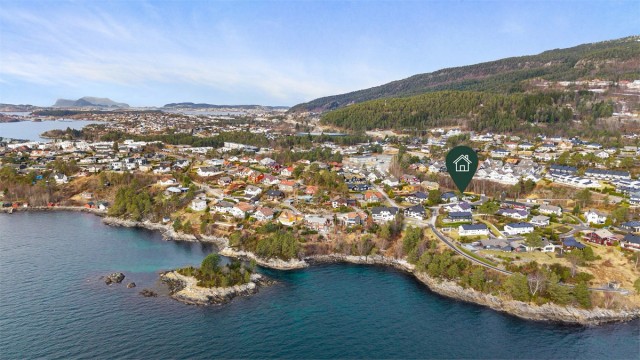Dronebilde av boligområdet tatt fra sjøsiden med eiendommens plassering markert