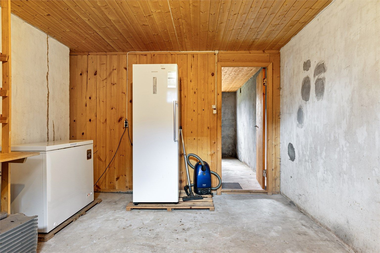 Alle gulvflater er i betong og veggene er i malte flater, panel og betong