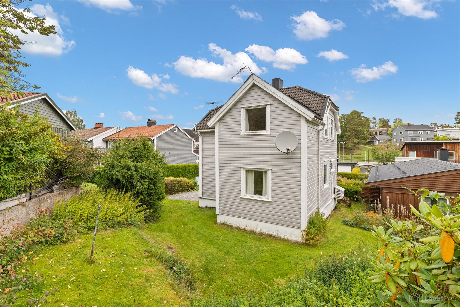 Hageområde med gressplen og frodige hekker rundt boligen.