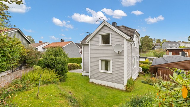 Hageområde med gressplen og frodige hekker rundt boligen.