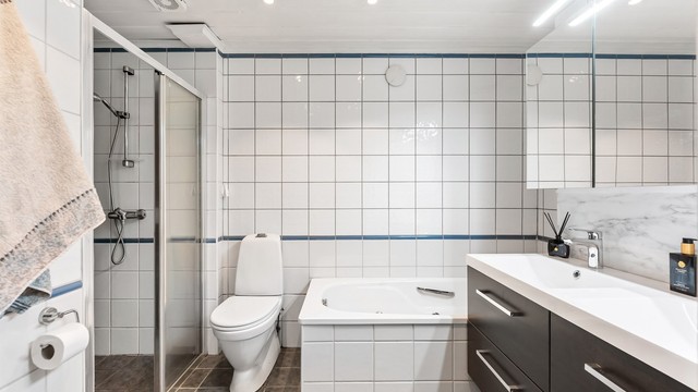 Det ene av to bad i underetasjen, utstyrt med både dusjnisje og badekar.