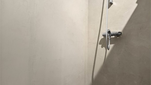 Romslig dusjnisje med vegger og gulv i mikrosement.