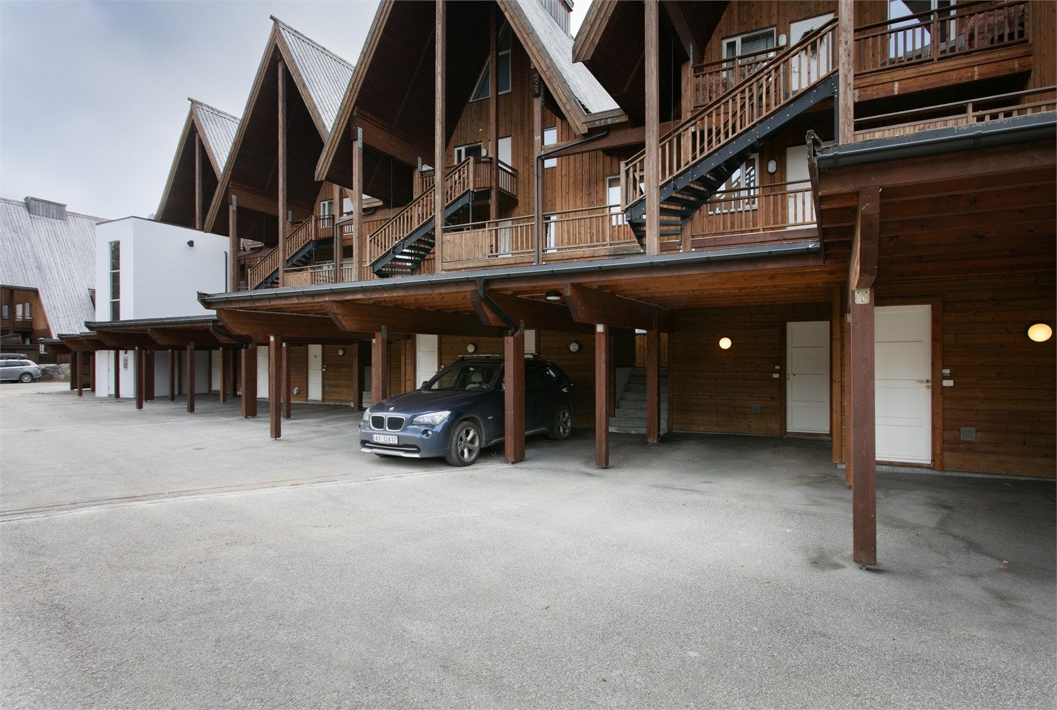Bilen parkeres under tak i carport, med tilhørende utvendig sportsbod.