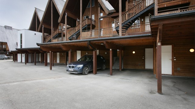 Bilen parkeres under tak i carport, med tilhørende utvendig sportsbod.