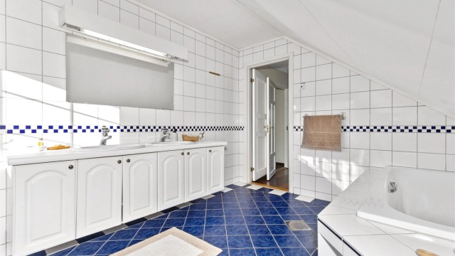 Baderomsinnredning med to nedsenkede vasker, underskap og stort speil med overbelysning.