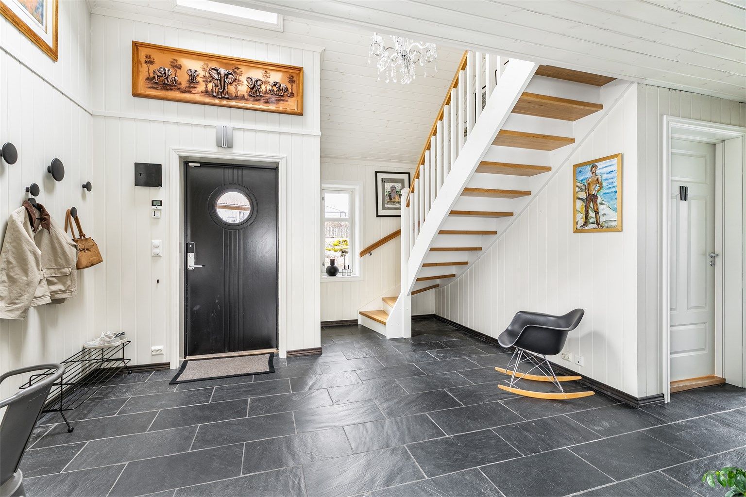 Den voluminøse hallen er et representativt første møte med boligens indre. Over hallen er det åpent mot loftstuen.