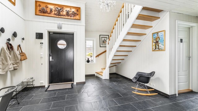 Den voluminøse hallen er et representativt første møte med boligens indre. Over hallen er det åpent mot loftstuen.