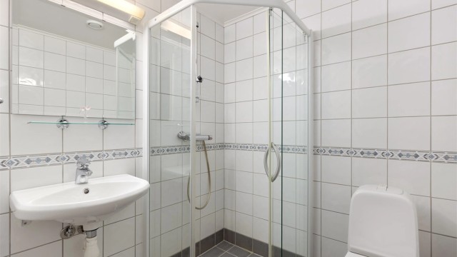 Bad 2 er flislagt med dusj, enkel servant og gulvstående WC