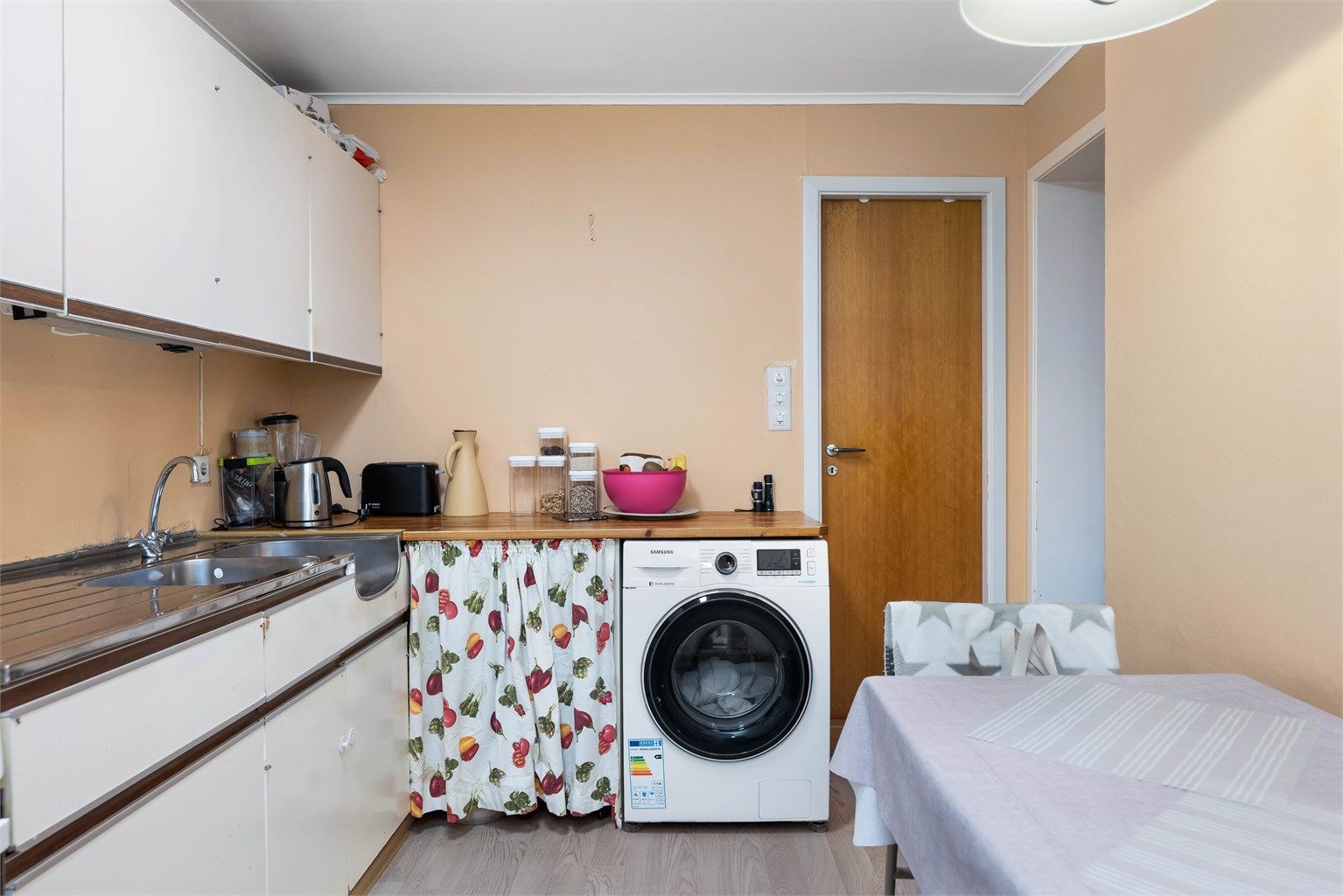 Innredning med benkeplate av tre, opplegg for vaskemaskin og nedfelt oppvaskkum.