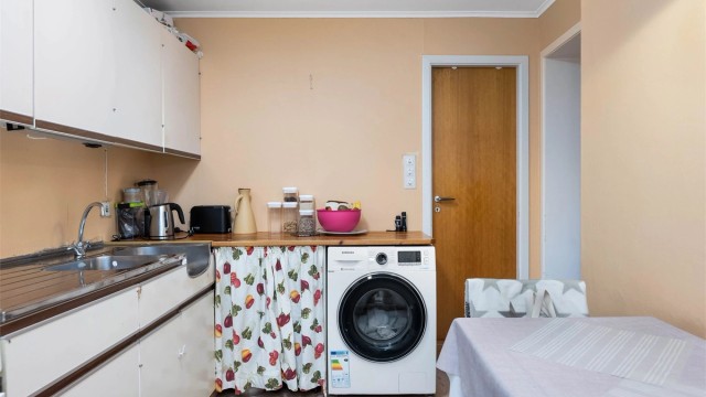 Innredning med benkeplate av tre, opplegg for vaskemaskin og nedfelt oppvaskkum.
