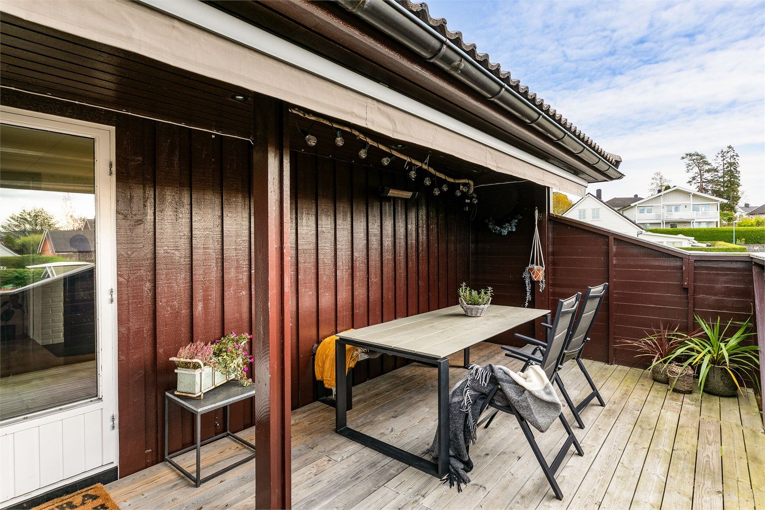 Terrassens heldekkende markise fungerer også perfekt som lunende tak på lyse sommerkvelder. Spotter ble innfelt i gesimskassene rundt boligen i 2024.