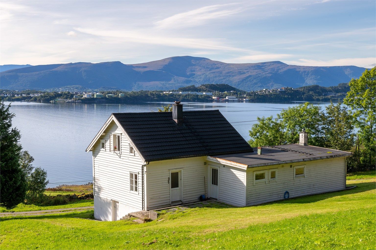 Boligen ligger tilbaketrukket i terrenget med åpent utsyn mot fjorden.