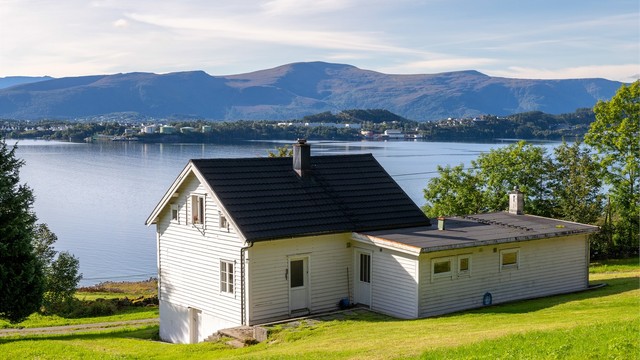 Boligen ligger tilbaketrukket i terrenget med åpent utsyn mot fjorden.
