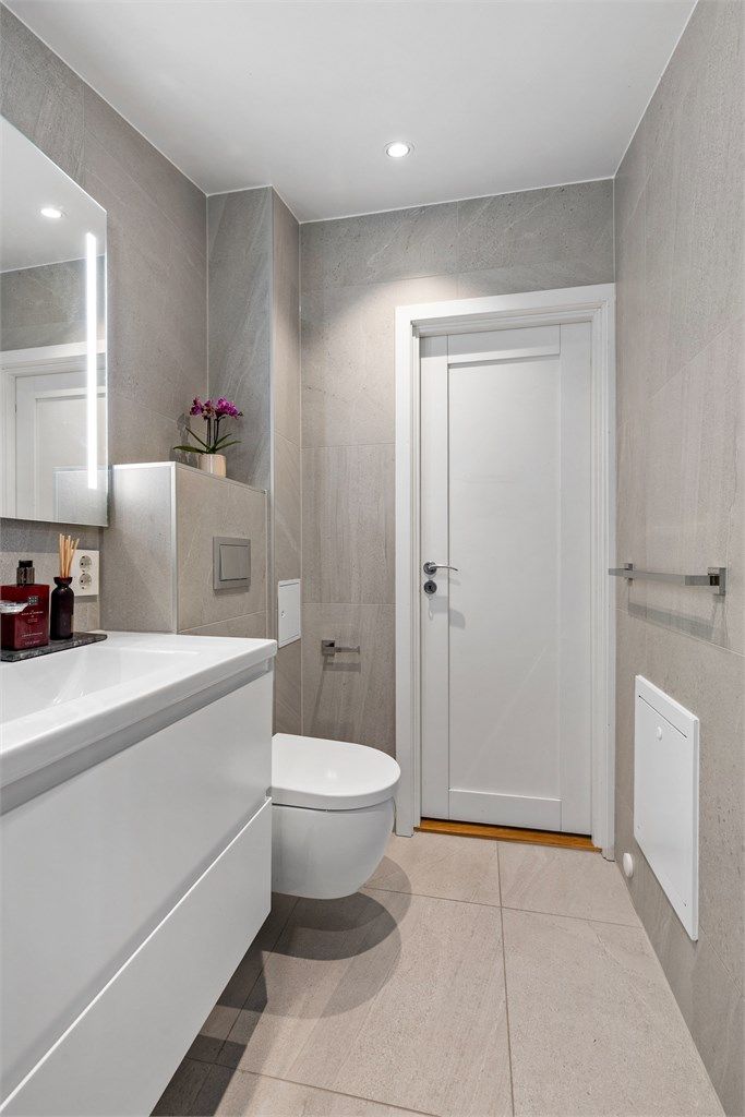 Baderom fra 2021. Flislagt gulv med gulvvarme. Flislagte vegger. Malte flater i himling. Vegghengt servantinnredning. Speil med sidelys.