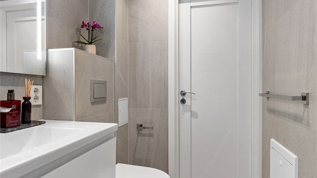 Baderom fra 2021. Flislagt gulv med gulvvarme. Flislagte vegger. Malte flater i himling. Vegghengt servantinnredning. Speil med sidelys.