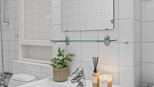 Vegghengt servantinnredning med speil og overbelysning.