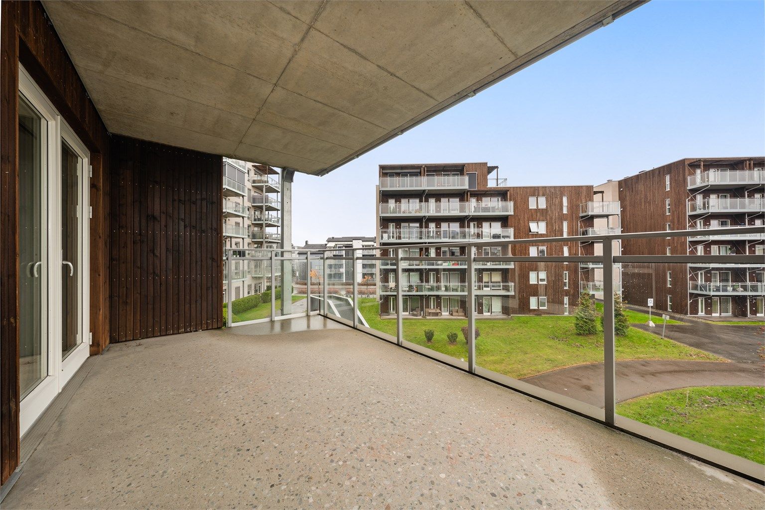 Lys og moderne selveierleilighet med stor, overbygd balkong vendt mot fellesarealene. Foto: Flytende Film AS (Thor Øyvind Borgersen)