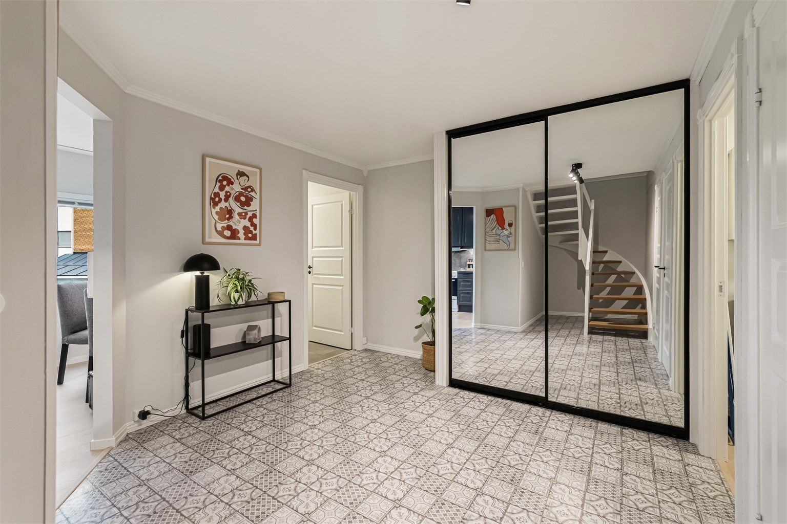 Romslig gang med stor skyvedørsgarderobe med speilfronter og mønstret gulvbelegg.