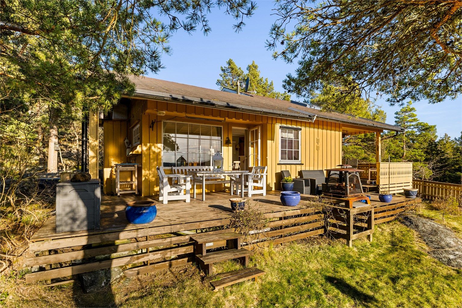 PÅ TERRASSEN: På hele hyttas vestside løper en stor og til dels overbygget terrasse. Takoverbygg gjør det lettvint å ha møbler stående ute og bidrar til lune uteplasser.