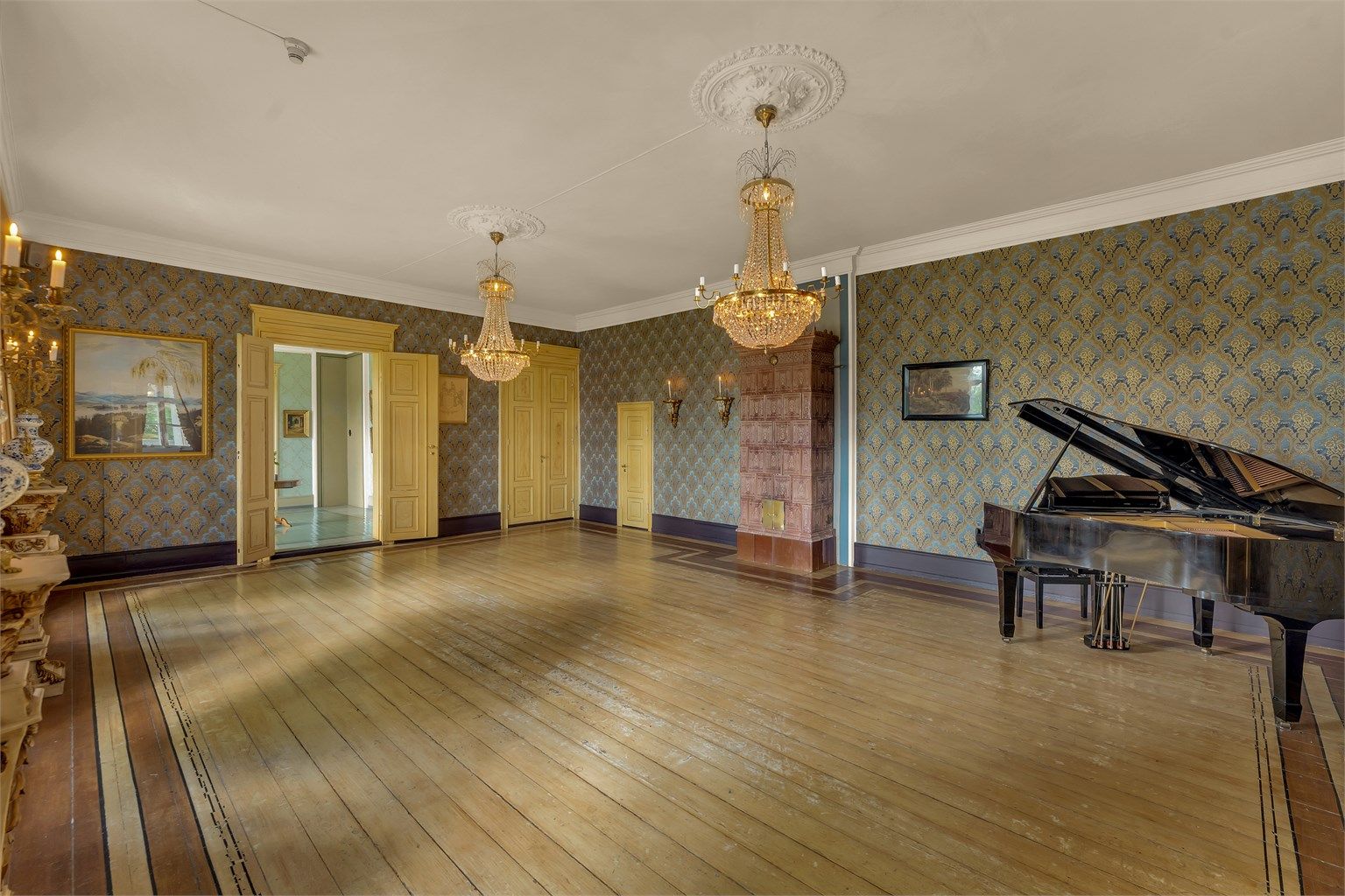 Den romslige salen, med sine høye tak, detaljerte takrosetter og tidløse design, gir et fantastisk inntrykk. Perfekt for storslåtte arrangementer, selskaper eller som en utstillingsarena for kunst og kultur