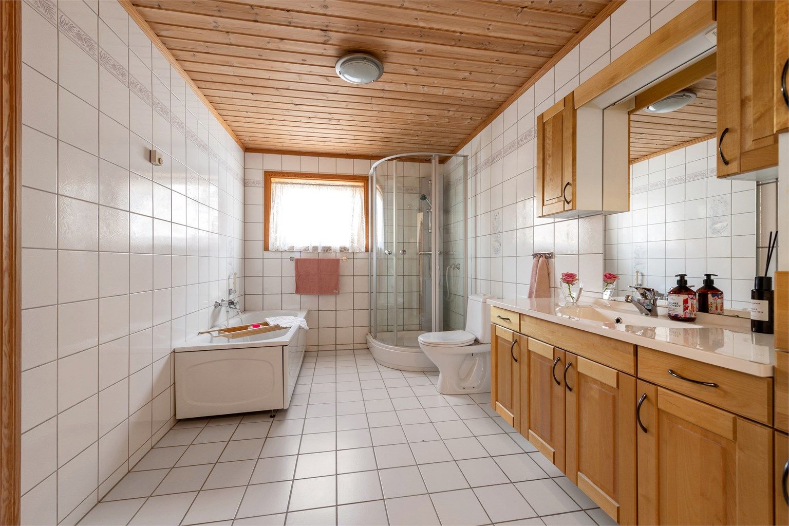 Romslig flislagt bad i hovedetasjen med stor innholdsrik og profilert baderomsinnredning med god skapplass. Frittstående badekar, dusjkabinett og toalett